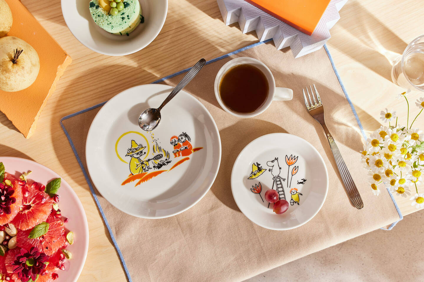 Arabia x Red Cross Moomin dinnerware displayed on a layer table