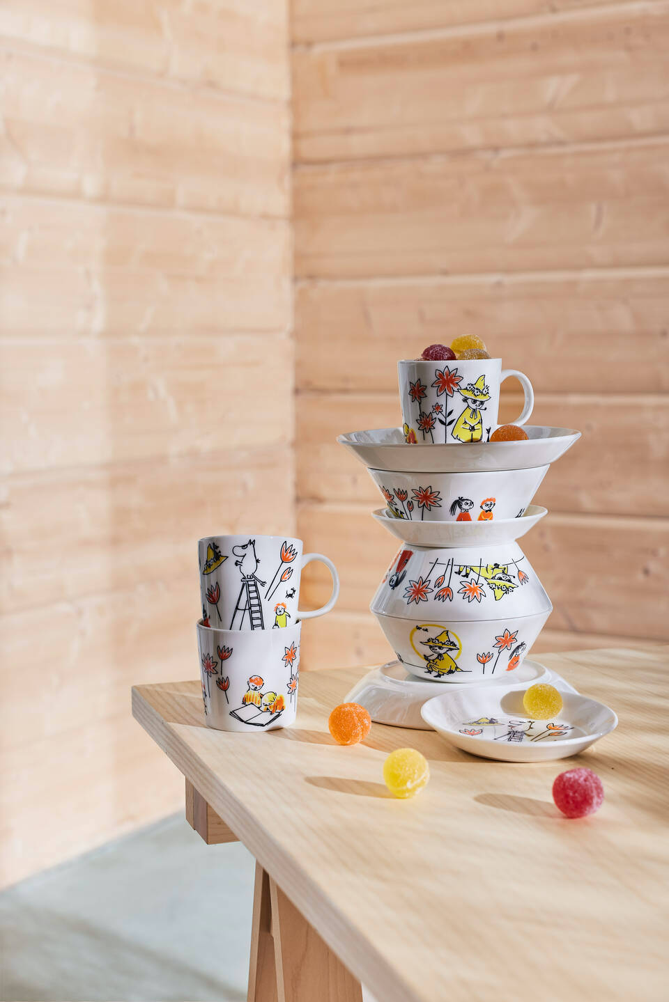 Arabia and Red Cross Moomin dinnerware collection stacked on table with sweets